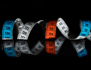 red, blue and white tape measure photographed on a black background