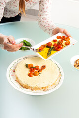 Close-up of the girl's hands decorating pesto cheesecake with cherry tomatoes