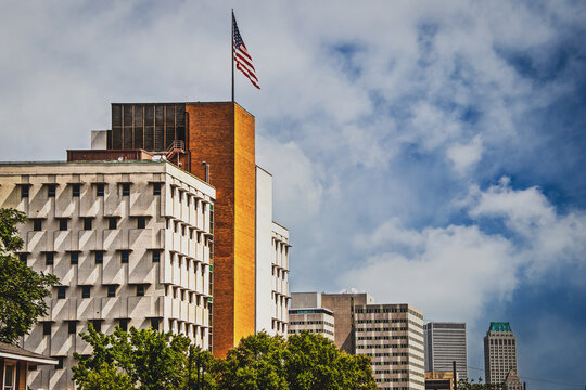 View Of Rooftops Of Downtown Tulsa With Old And New Buildings And American Flag Flying High Over It All Under Pretty Sky.