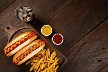 Hot dogs with ketchup, yellow mustard, french fries and soda. Image with selective focus