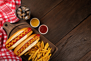 Hot dogs with ketchup, yellow mustard, french fries and soda. Image with selective focus