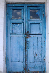 Old wooden door with lock painted in blue. Cracked weathered wooden texture. 