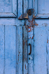 Old wooden door with lock painted in blue. Cracked weathered wooden texture. 
