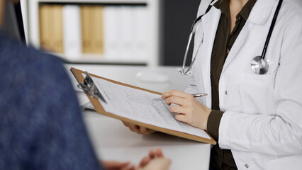 Doctor and patient discussing current health examination while sitting in clinic. Perfect medical...