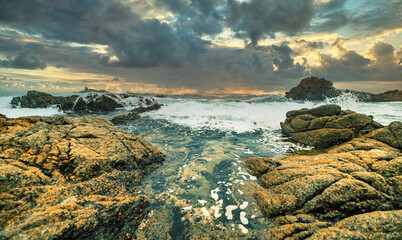 Beautiful seascape, ocean views, rocky coast, sunlight on the horizon. Composition of nature. Sunset scenery background. Cloudy sky. Water Reflection. California Seashore.