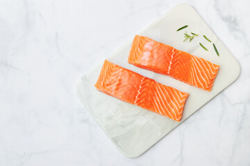 Fresh salmon fillet with rosemary on marble plate for delicious salmon steak. Top view with copy...