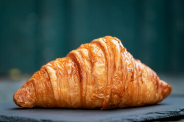 Freshly baked croissants just out of the oven on black stone background.