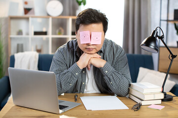 Man sleeping at work with fake eyes painted on paper sticker, covered his eyes