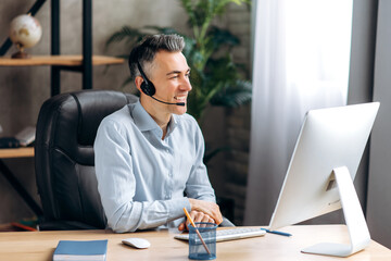 A joyful caucasian senior business leader, manager, sits at a table, at the office, in a stylish...