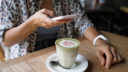 Blogger taking a picture of green tea matcha latte decorated with flowers. Healthy organic plant based drinks