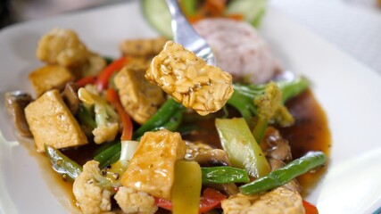 Vegan asian food. Close up of tofu stew with lots of veggies and rice on a side 
