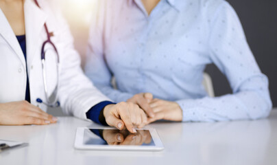 Unknown woman-doctor is showing to her patient a description of medication, while sitting together...