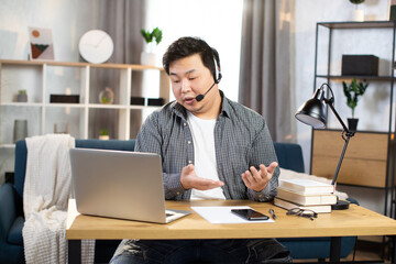 Fototapeta na wymiar Asian man using headset and laptop for video chat