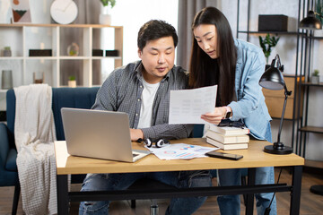 Confident young Asian business partners discussing common project at work