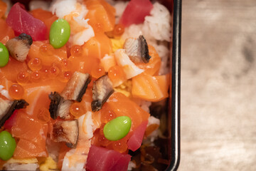 Box of chirashi sushi with mixed raw fish and salmon roe over rice