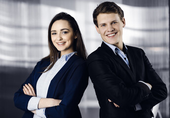 Friendly young colleagues are standing as a team with crossed arms in a modern office. Portrait of successful business people at work