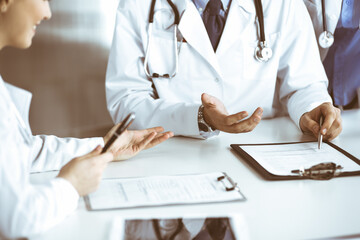 Group of unknown doctors are sitting at the desk and discussing problems or disease treatment in modern hospital office. Coronavirus countering, patient help in medicine concept