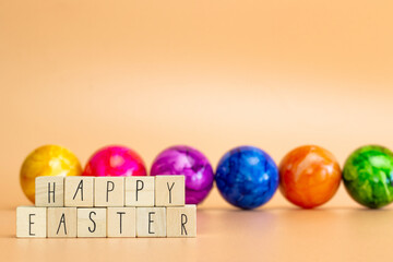 Happy Easter written with pastel colored orange background and colorful fainted Easter eggs, Bright fresh colors, Spring,Easter Holiday, greeting card concept with copy space