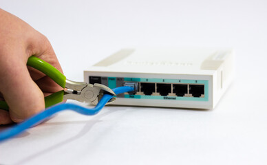 Cuts cable on router. Man cuts cord of Wi-Fi router. White router with cut cord. Side cutters cut...