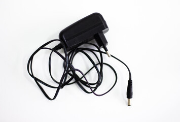 Black power adapter on white background. Charging adapter with cable. DC + 5 ~ 9V 5.5 * 2.1MM adapter on white background. Black power supply with cable on white background.
