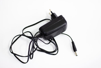 Black power adapter on white background. Charging adapter with cable. DC + 5 ~ 9V 5.5 * 2.1MM adapter on white background. Black power supply with cable on white background.