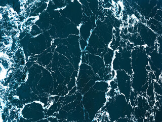 Full frame aerial view of ocean surface and waves - natural abstract dark blue background. Trendy cinematic color grading.