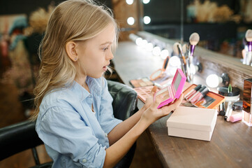 Little girl applies pomade in makeup salon