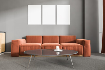 Brown sofa in grey living room interior with three posters