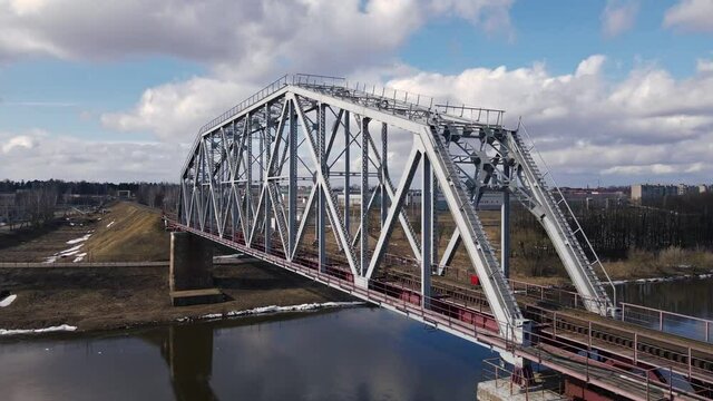 Metal railway train bridge over the river Belarus Orsha Dnieper River. early spring Aerial footage from a drone flying close along the bridge