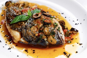 Grilled dorada fish with honey sauce, olives, spices, tomatoes
