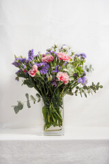 bouquet of flowers with carnations and lilacs in glass vase isolated on white background 
