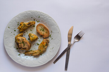 plate with stewed chicken pieces and a knife and fork, isolated on white background