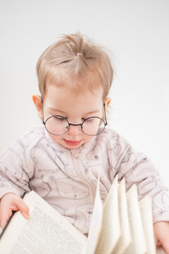 Cute toddler girl in glasses reading book on white background. Back to school concept