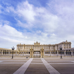 Obraz premium Main facade of the royal palace of Madrid with its huge esplanade and blue sky with clouds at sunrise.