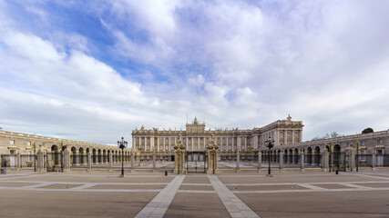 Obraz premium Main facade of the royal palace of Madrid with its huge esplanade and blue sky with clouds at sunrise.
