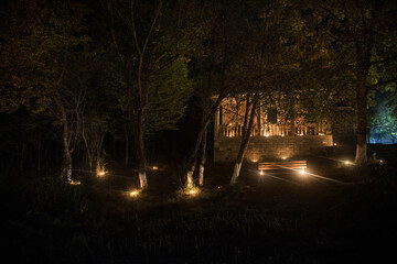 Mountain night landscape of building at forest at night with moon or vintage country house at night with clouds and stars. Summer night.