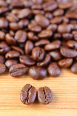 Vertical Image of Arabica VS Robusta Roasted Coffee Beans with Blurry Coffee Beans Pile in Background