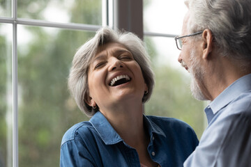 Close up shot of aged family couple have fun at home laugh recalling amusing incident from youth in...
