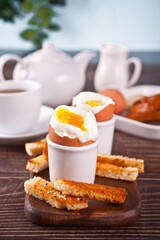 boiled egg in eggcup on wooden board with crispy toast.