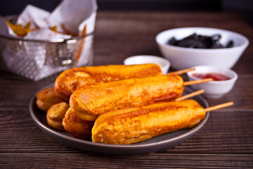 Corndogs on a stick with ketchup and mustard on the wooden table.