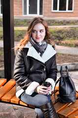 Fototapeta na wymiar Shot of beautiful brunette girl with takeaway drink on the street. scarf and autumn coat in the city. view of business lady with a cup of coffee walking down the street.