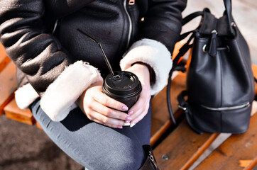 Shot of beautiful brunette girl with takeaway drink on the street. scarf and autumn coat in the city. view of business lady with a cup of coffee walking down the street.