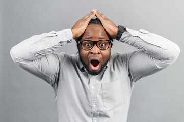 Portrait of forgetful young African American customer or employee wearing shirt looking with shocked and guilty expression, holding hands on his head, opening mouth widely, body language, Oh no - obrazy, fototapety, plakaty