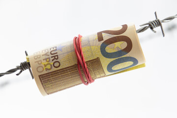 200 euro bank notes rolled up and hanging on barbed wire