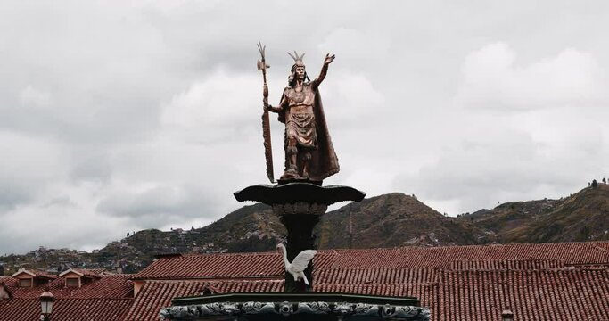 Golden Atahualpa statue in Main plaza cuzco with roofs and mountains - Timelapse