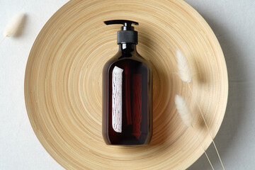 Dark amber glass bottle and dried flowers on plate. Natural skincare SPA beauty product design....