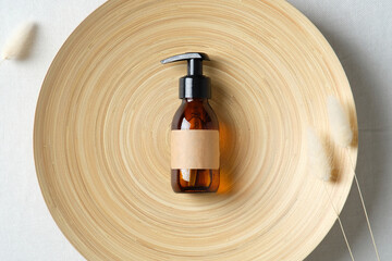 Amber glass pump cosmetic bottle mockup on plate. SPA natural organic cosmetics for personal hygiene. Flat lay, top view.