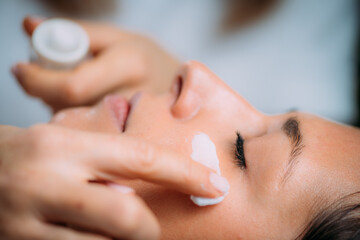 Obraz na płótnie Canvas Cosmetician Applying Cream on Woman’s Face