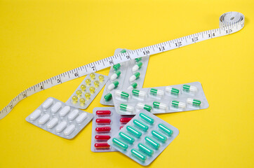medical pills and measuring tape lie on a yellow background