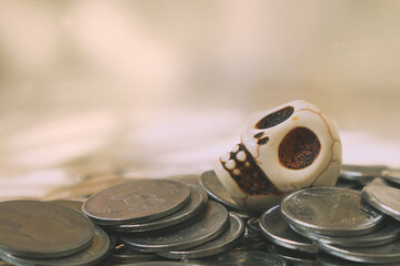 The toy human skull lies on the Indian coins rupees. Space for text.